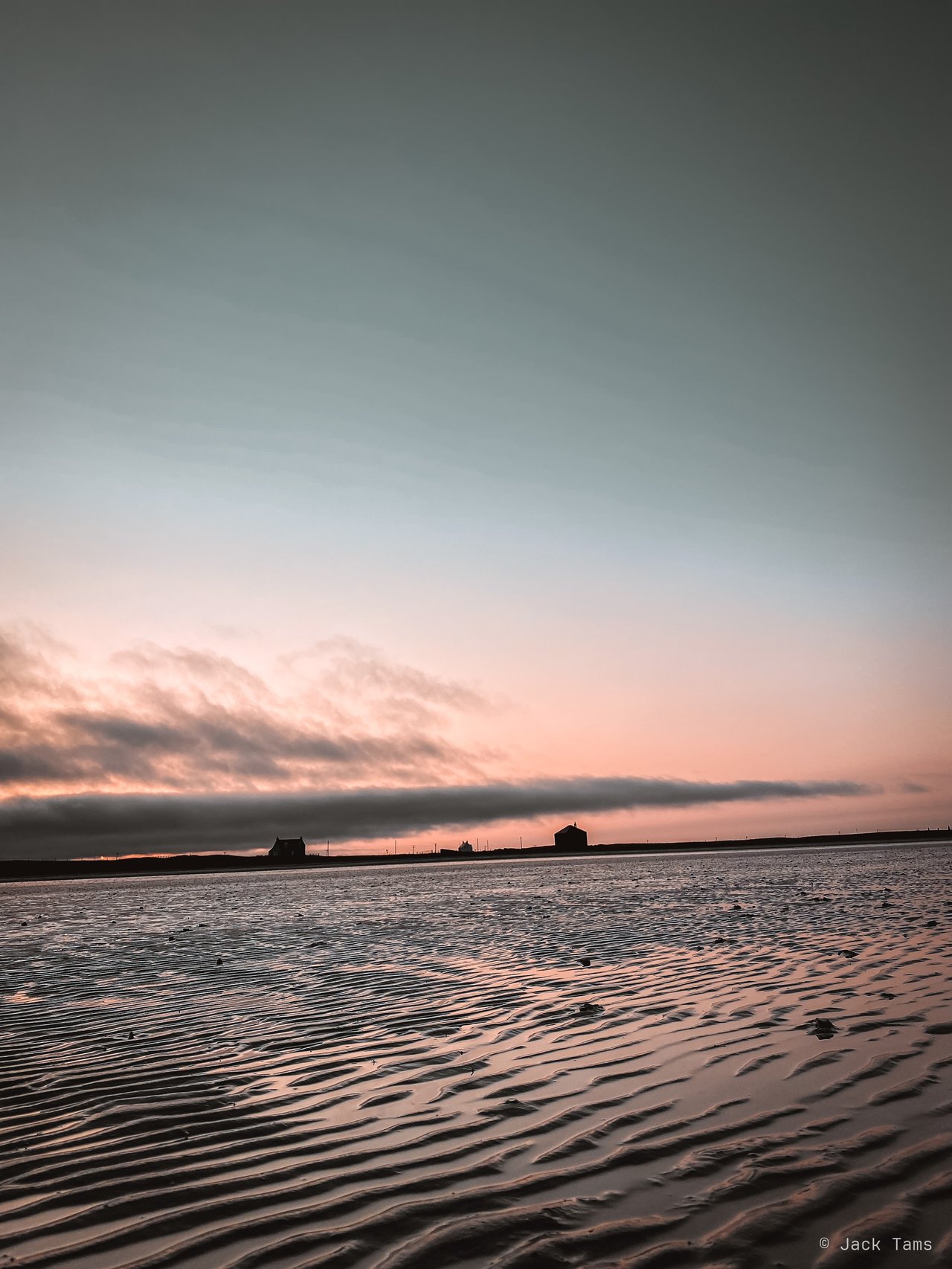 Sand ripples at low tide under a pink sky.