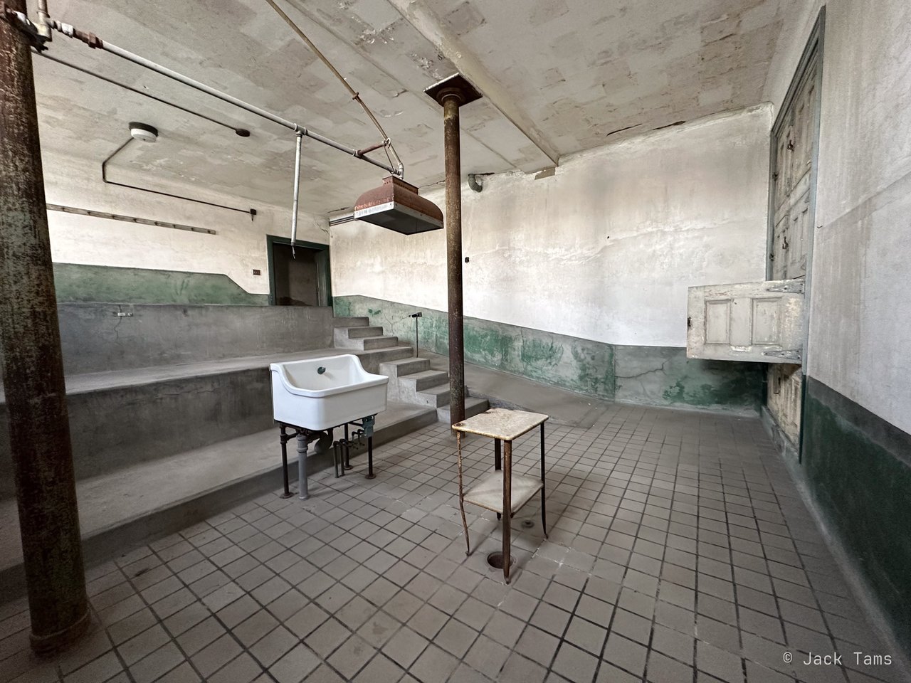 A tiled ward with a sink and a chair, left as it was.
