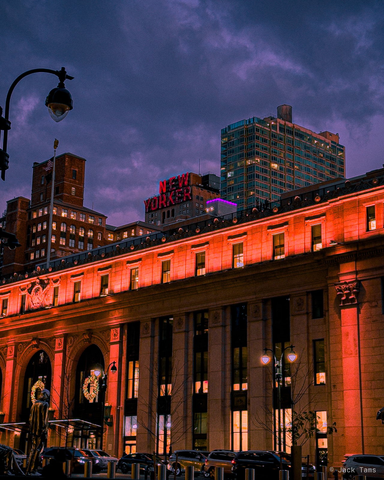 A grand old building lit red at dusk.