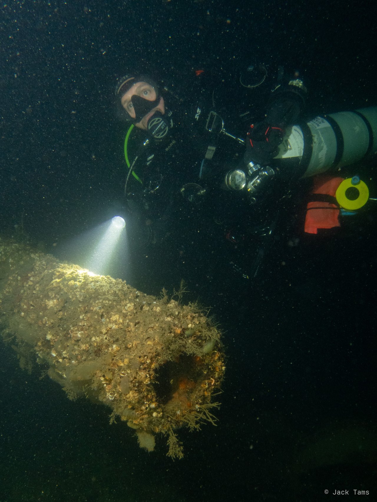 A diver lighting up a gun barrel.