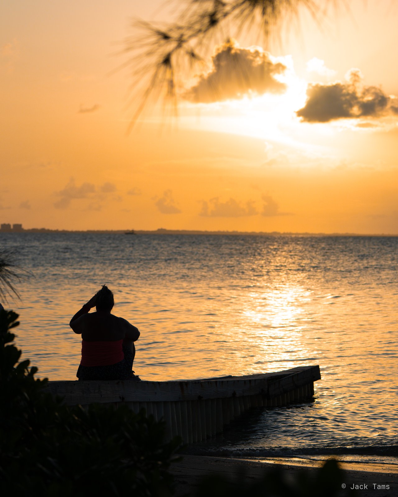 Someone watching the sunset from the end of the jetty.