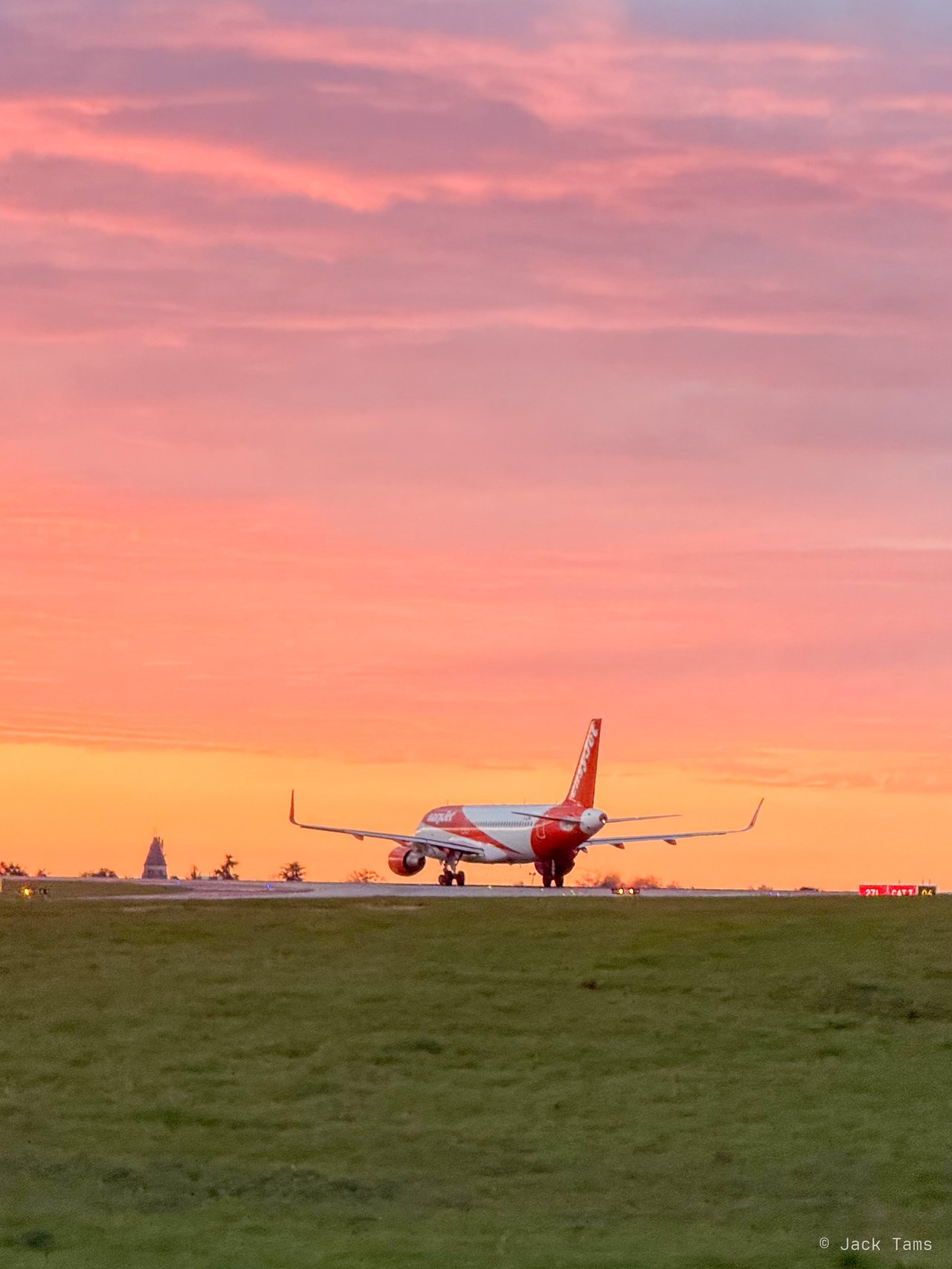 A plane on the apron under a pink sunset sky, heading home.