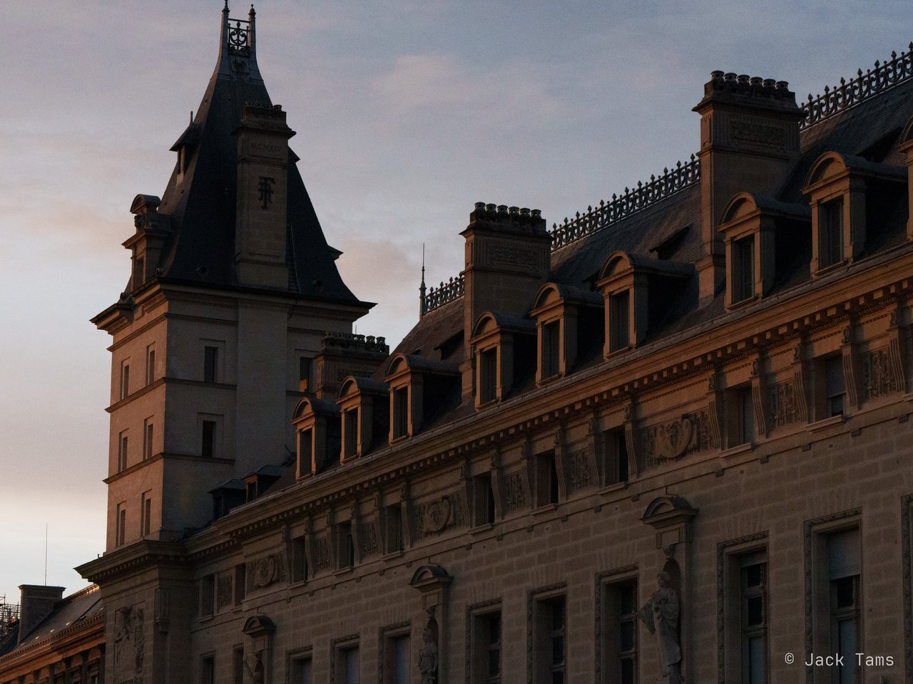 Mansard roofs and turrets at dusk.