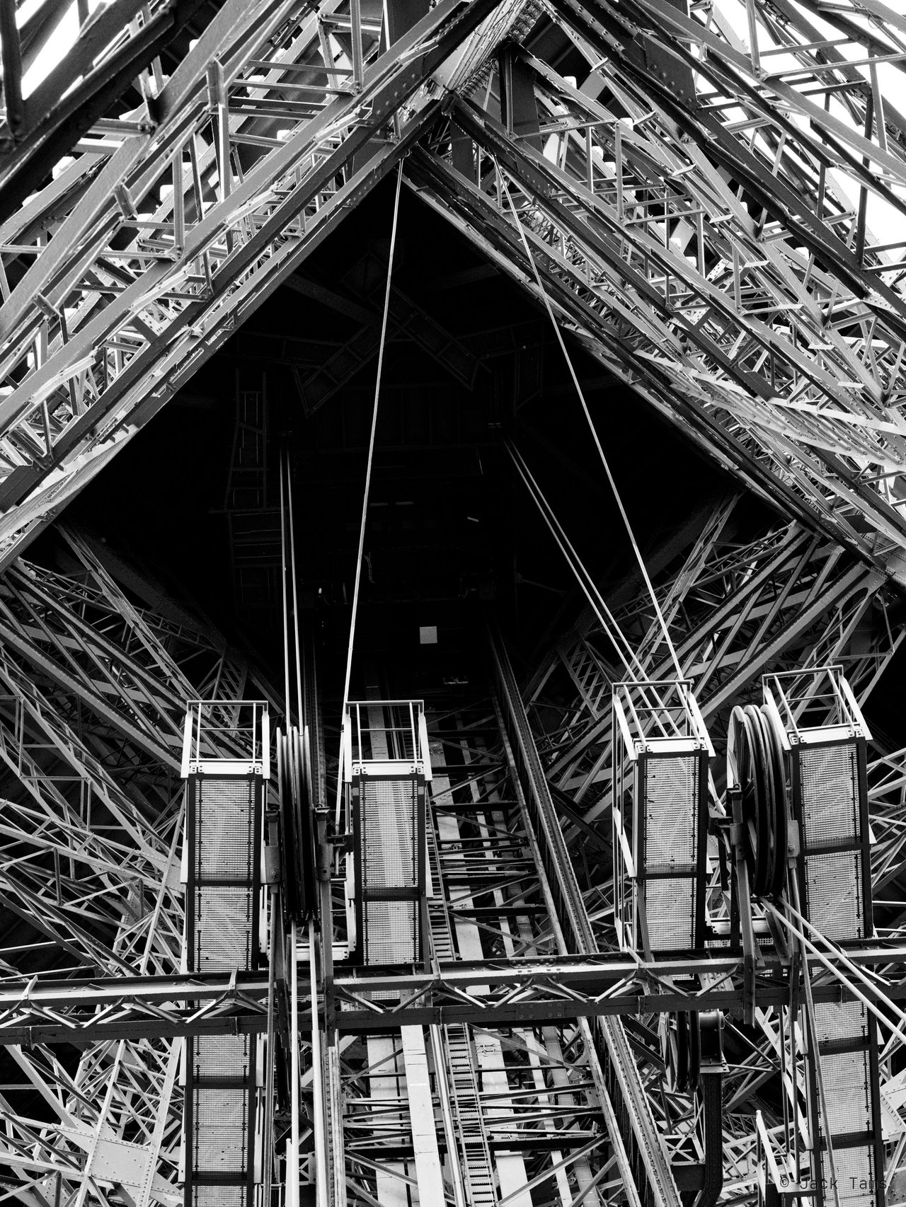 Inside the Eiffel Tower's legs, in black and white.