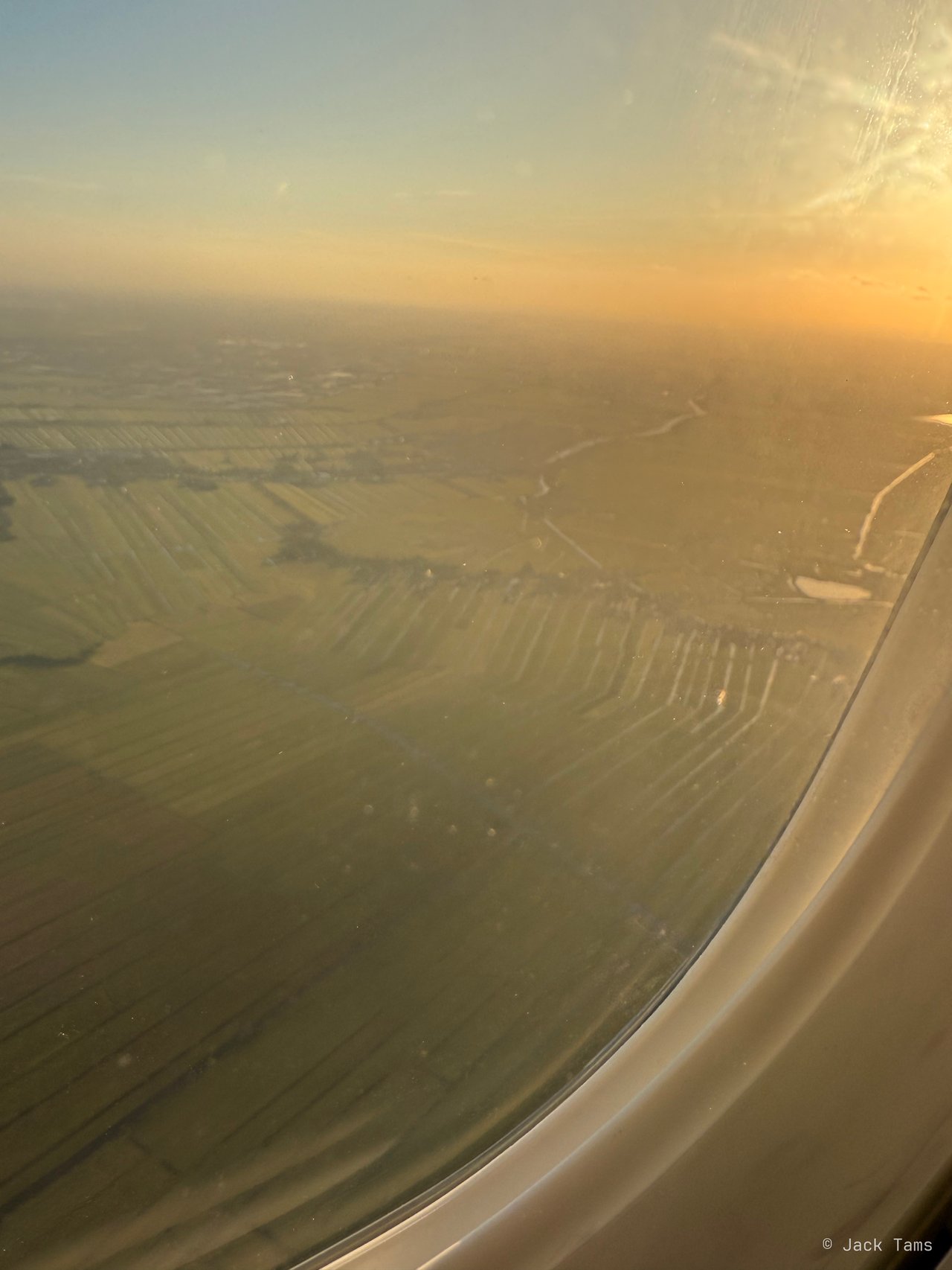 Low golden light over the polders on the approach to Schiphol.