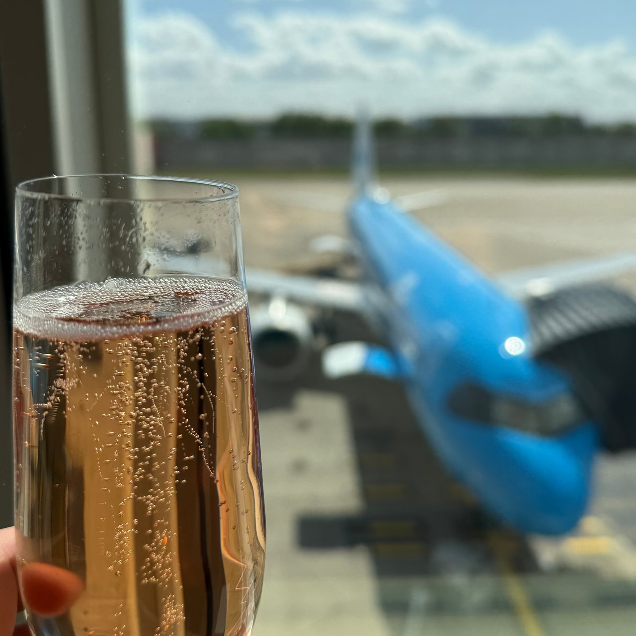 A glass of rosé Champagne at the lounge window, the KLM A320 at the gate.