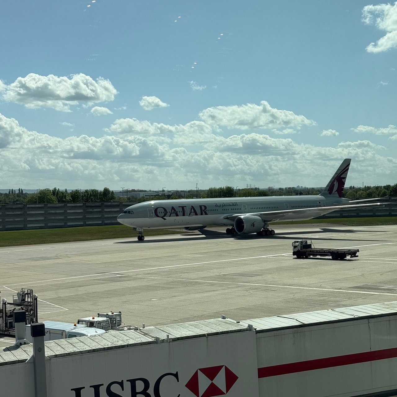 The Qatar 777 at the gate, the HSBC airbridge in the foreground.