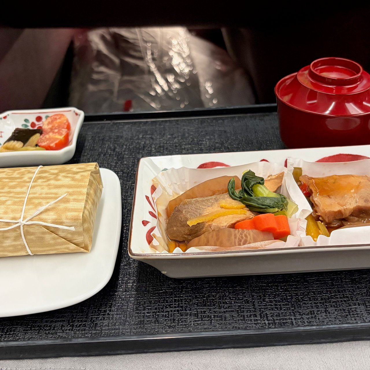 Simmered yellowtail and radish with pak choi, carrot and yuzu peel, and roast pork with marinated vegetables; steamed rice, miso soup and Japanese pickles.